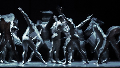 A group of dancers whose gestural movements are blurred. 