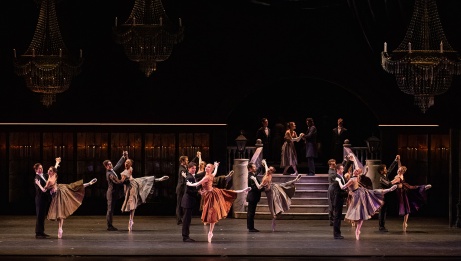 In a ballroom setting, 8 couples wear formal attire, the women on pointe with legs extended. 
