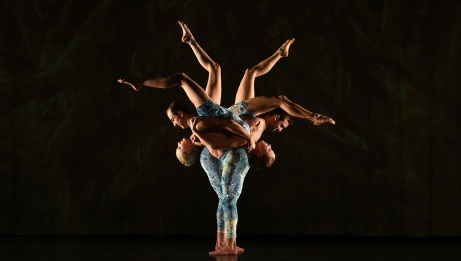 4 dancers, two of which are carried upside down, create an acrobatic illusion against a black background. 