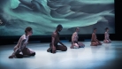 Five dancers, all bare-chested, kneel on stage in front of a projected photograph in undergarments.  © Rodfolfo Rueda