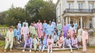 The Kingdom Choir in pastel outfits posing in front of a mansion 