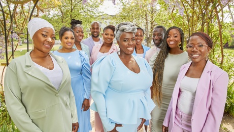 The Kingdom Choir in pastel outfits posing in a garden 