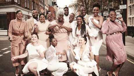 The Kingdom Choir in beige outfits posing in the street 