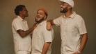 Trois hommes vêtus de lin blanc souriant et posant pour la caméra.  