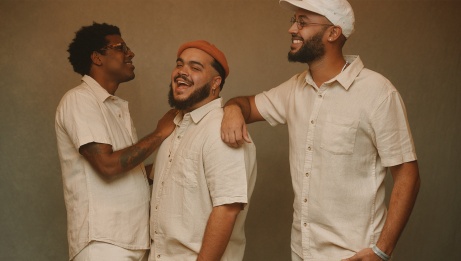 Three men dressed in white linen smiling and posing for the camera 