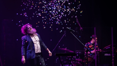 Ben Caplan on stage surrounded by falling confetti