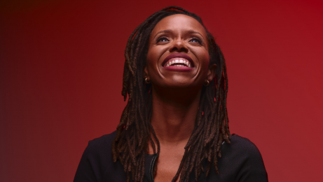 Kellylee Evans on a red background  smiling and look upwards
