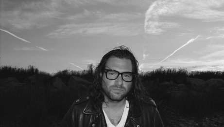 Adam Baldwin in black and white, in a field.