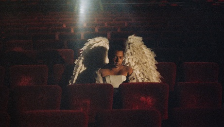 Fernie with angel wings, sitting in a theatre in the dark.