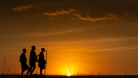 Three people in front of a sunset 