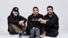 The 3 band members sitting on the floor in front of a white background. © Curtis Perry