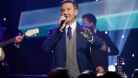 Daniel O'Donnell qui porte un bel habit bleu foncé et qui chante sur scène.  