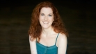 Genna smiling and looking at the camera. She's wearing a turquoise tank top and she has red curly hair. © David Leyes 