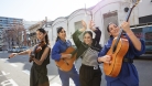 Las Migas in the street, holding instruments and dancing. 