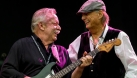 The guitarist and singer from Downchild on stage smiling. 