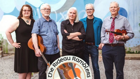 Les cinq membres des Rideau Ramblers à l'extérieur. Un membre tient sa guitare et un autre son violon.