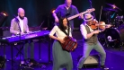 Performers on stage playing the violin, bass, keyboard and accordion. © Graham Lindsey