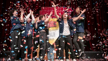 An improv team on stage during their victory. Everyone's celebrating and smiling, and there's confetti everywhere.