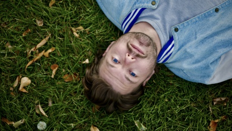 Étienne Fletcher is lying down in the grass.