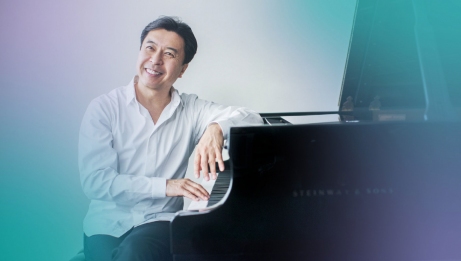 Makoto Ozone smiling in front of a grand piano