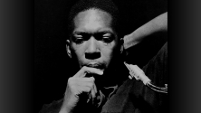 Photo en noir et blanc de John Coltrane, l'air pensif, le menton pos&eacute; sur sa main, dans une attitude de r&eacute;flexion. 