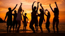 Un groupe de personnes profitant de la plage au coucher du soleil, avec des couleurs &eacute;clatantes dans le ciel et les silhouettes des personnes se d&eacute;coupant sur l'horizon. 