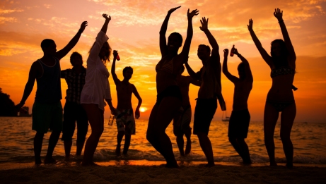 Un groupe de personnes profitant de la plage au coucher du soleil, avec des couleurs &eacute;clatantes dans le ciel et les silhouettes des personnes se d&eacute;coupant sur l'horizon.