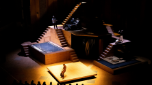 Grand d&eacute;cor de th&eacute;&acirc;tre compos&eacute; de plateformes et d&rsquo;escaliers, &eacute;clair&eacute; de fa&ccedil;on dramatique, avec des interpr&egrave;tes r&eacute;partis sur la sc&egrave;ne. © Joachim Bertrand
